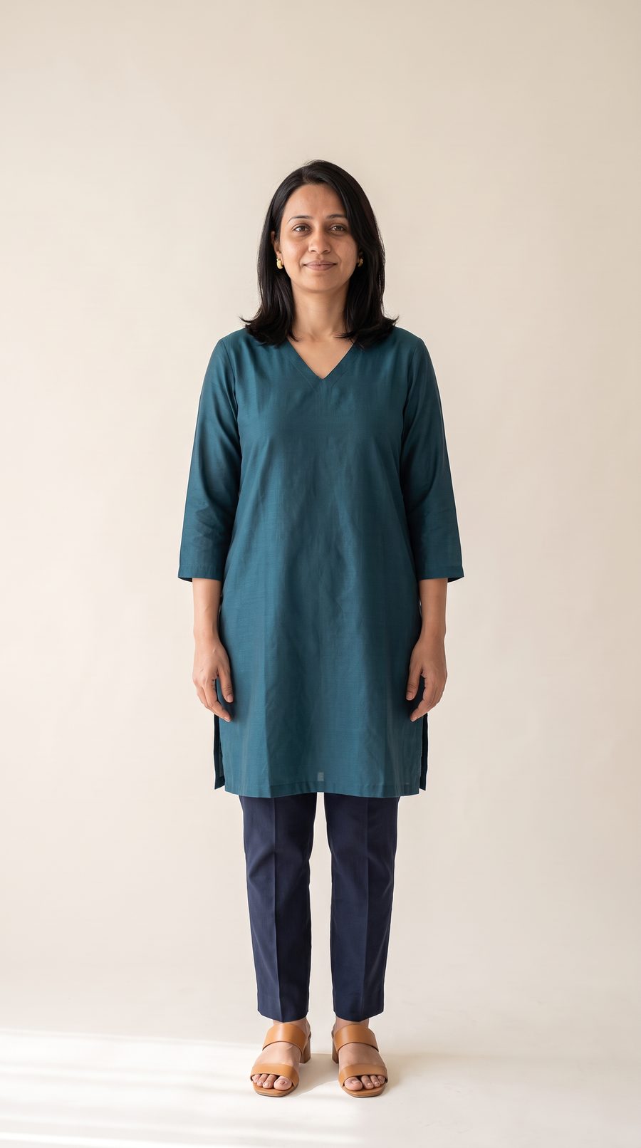 The same woman in a deep teal kurta with a V neckline and soft layers around the face